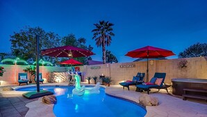 A pool area with lounge chairs, red umbrellas, and a hot tub. - Spacious 8-bedroom house in phenomenal Glendale with AC and gym (Glendale)
