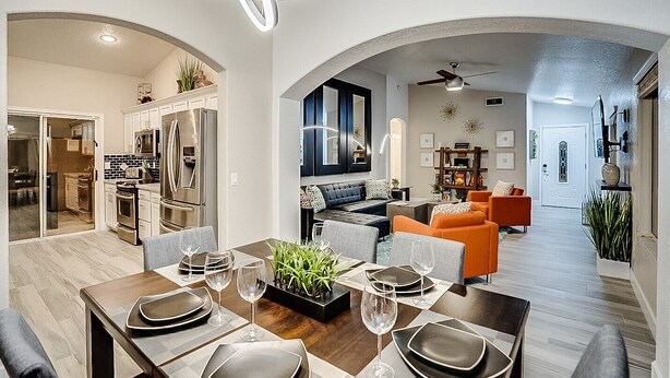 A modern kitchen with stainless steel appliances, a dining area with a wooden table set for four, and a living room with a sofa and a coffee table. - Spacious 8-bedroom house in phenomenal Glendale with AC and gym (Glendale)