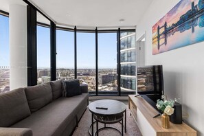 A modern living room with a large window, a sofa, a coffee table, and a painting of a bridge. - City Lights Retreat – Fortitude Valley (Brisbane)