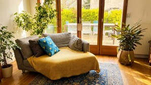 Ein gemütliches Wohnzimmer mit einer Couch, einem gemusterten Teppich und Topfpflanzen.