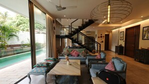A spacious living room with a large window, a staircase, and a pool view. - Euphoria by Dia Hotels And Homes (Nerul)
