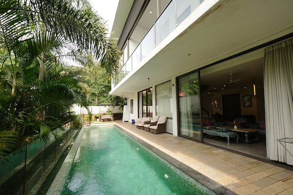 A modern house with a swimming pool, outdoor seating, and large windows.