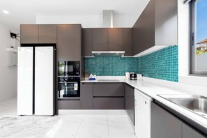 A modern kitchen with grey cabinets, a white refrigerator, a built-in oven, and a teal backsplash. - 3BR Pool Villa with Bathtub  V294 (Rawai)