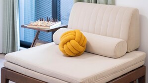 A bed with a yellow pillow, a chessboard, and curtains. - The Peak Bentencho (Osaka)