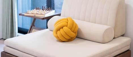 A bed with a yellow pillow, a chessboard, and curtains.