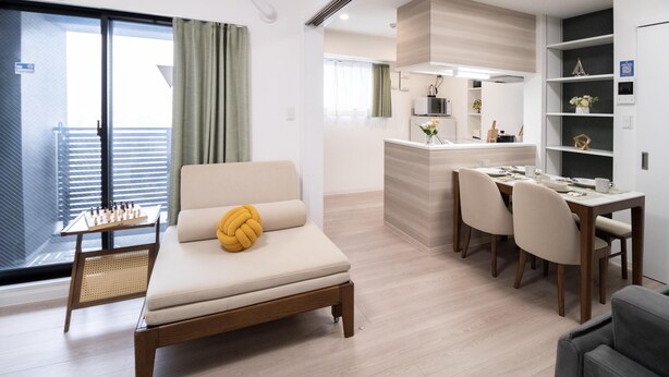 A modern living room with a sofa, a dining table with chairs, a small kitchen area, and a balcony with a view. - The Peak Bentencho (Osaka)