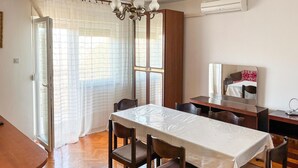 A dining area with a table set for four, wooden chairs, a chandelier, a wooden cabinet, and a large mirror. - 3 bedroom pet friendly apartment in Senj (Senj)