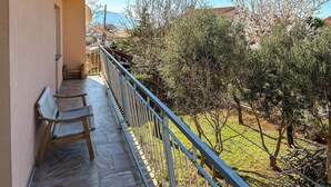 A balcony with a wooden bench, a metal railing, and a view of olive trees and a mountain in the background. - 3 bedroom pet friendly apartment in Senj (Senj)