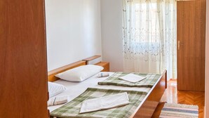 A room with two single beds, wooden headboards, a wooden wardrobe, and a window with sheer curtains. - 3 bedroom pet friendly apartment in Senj (Senj)