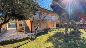 A modern house with a stone staircase leading to a door, surrounded by a well-maintained lawn and trees. - 3 bedroom pet friendly apartment in Senj (Senj)