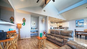 Amplia sala de estar con sofá de cuero, mesa de centro de madera y comedor con mesa y sillas de madera.