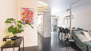A modern living room with a dining area, a staircase, and a kitchen in the background. - Character & Charm 3BR home - free wine (Adelaide)