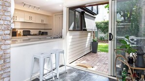 A modern kitchen with white cabinets, a built-in oven, and a sliding glass door leading to a patio. - Character & Charm 3BR home - free wine (Adelaide)