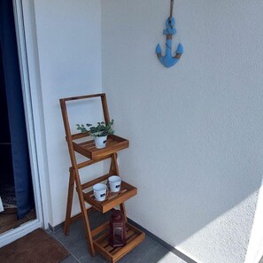 A wooden shelf with a potted plant, two white cups, and a lantern. - Ugodan apartman sa prekrasnom terasom u mirnoj ulici u blizini plaže (Vodice)