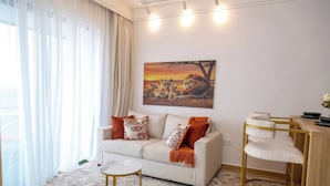 Uma sala de estar com sofá, mesa de centro, pintura de leões e um espaço de refeições com uma cadeira.