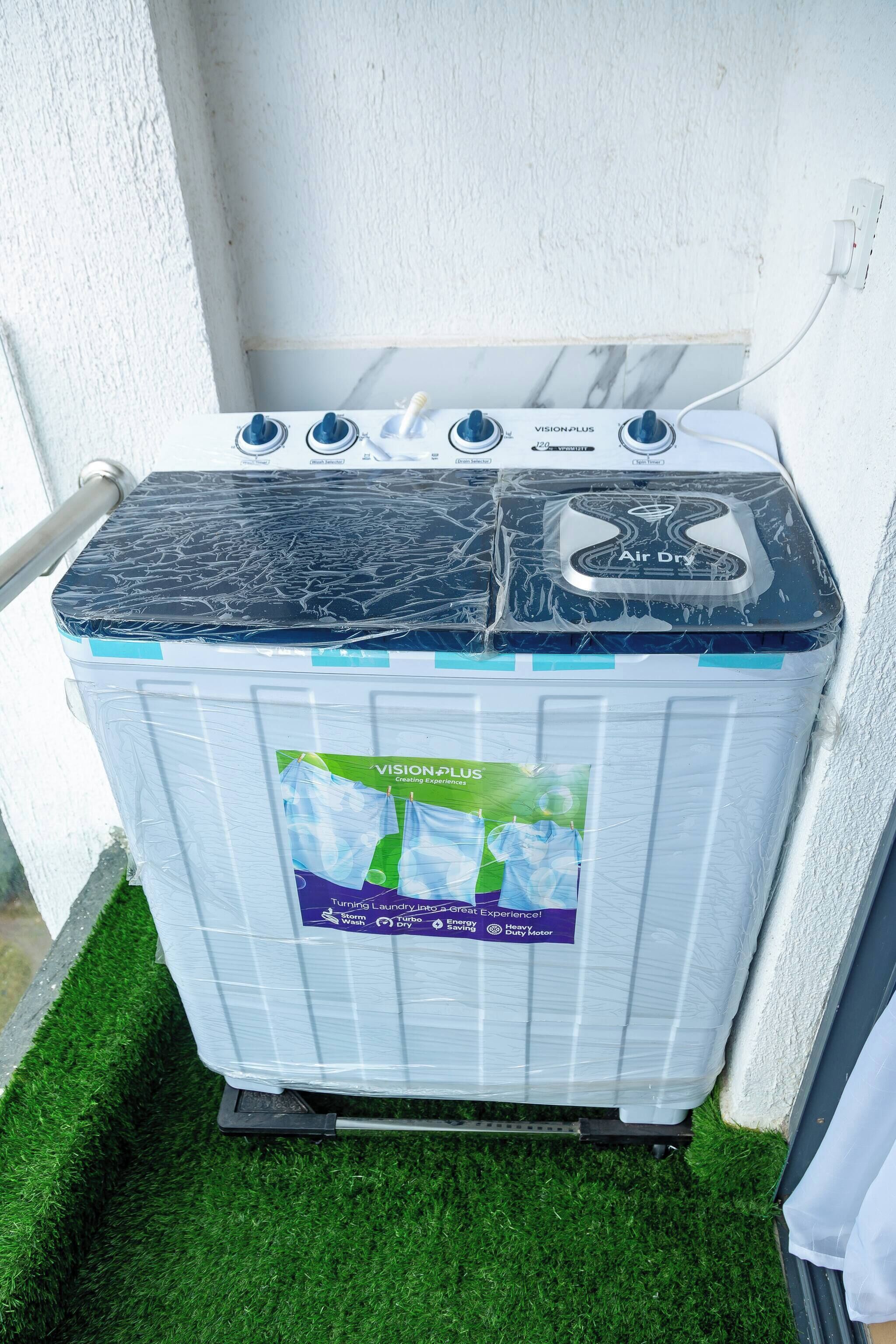 A white washing machine with a blue top and a label reading "VISION PLUS" and "Air Dry".