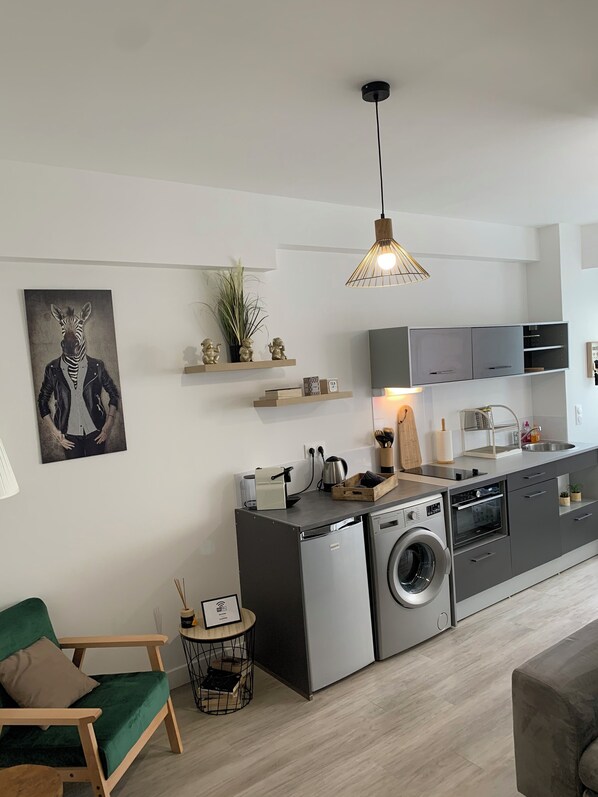 A modern kitchen with a built-in washing machine, a sink, and a dining area with a green sofa.