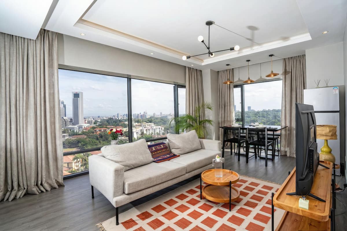 Un salón moderno con sofá, mesa de comedor y ventanas amplias que ofrecen vistas a la ciudad.