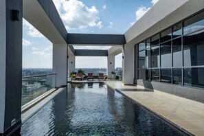 A rooftop infinity pool with a clear view of the city skyline, surrounded by modern architecture and large windows. - Tamu Residence (Nairobi)