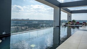 En modern inomhuspool med en fantastisk panoramautsikt över staden, ett avslappningsområde med fåtöljer och en klar himmel.