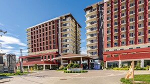 A modern hotel with multiple floors, a covered entrance, and a landscaped courtyard. - Cozy and Nature-Inspired Studio Unit (Lapu-Lapu)