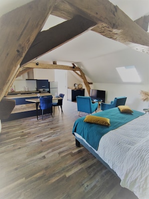 Ein Schlafzimmer im Dachgeschoss mit Bett, Stühlen und Schreibtisch.