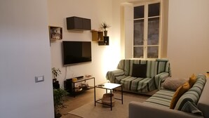 A living room with a sofa, a coffee table, a TV, and a window. - Apartment in the historic center (Camaiore)
