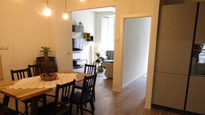 A dining area with a wooden table and chairs, a white doily, and a potted plant. - Apartment in the historic center (Camaiore)