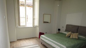 A bedroom with a bed, a window, a mirror, and a rug. - Apartment in the historic center (Camaiore)