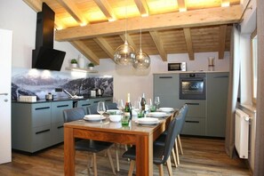 Eine moderne Küche mit Essbereich, Holzbalkendecke und Pendelleuchten.