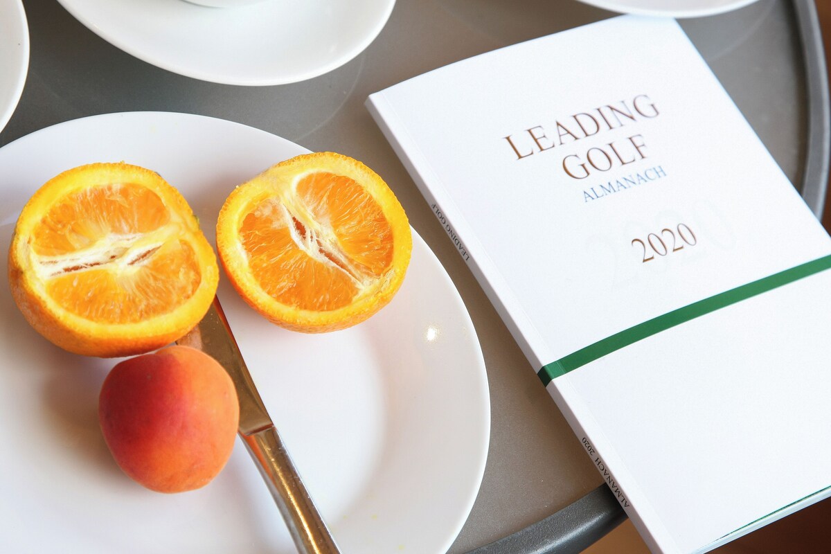 A book titled "Leading Golf Almanach 2020" on a tray with a plate of fruit.
