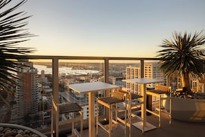 Ein hoher Balkon mit Stadtblick, zwei Tische und Stühle.