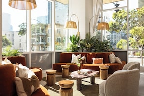 Ein modernes Wohnzimmer mit einer Couch, einem Couchtisch und Holzschemeln. Große Fenster bieten Blick auf die Stadt.