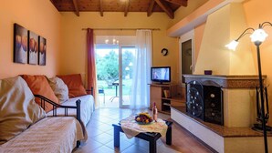 Ein gemütliches Wohnzimmer mit Kamin, Fernseher und Essbereich mit Tisch für zwei Personen.