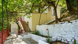 Un estrecho sendero de piedra que conduce a un edificio con una escalera roja y una pared blanca.