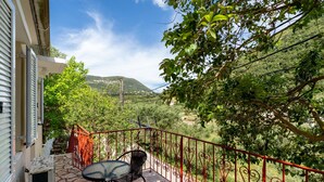A balcony with a table and chairs, a red railing, and a view of a green landscape with hills. - Villa Liana Country House with Sea View (Φρίκες)