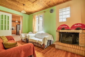 A cozy room with a bed, a sofa, a fireplace, and a kitchen area visible through an open door.