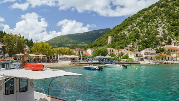 A coastal village with boats, buildings, and a hill in the background. - Villa Liana Country House with Sea View (Φρίκες)