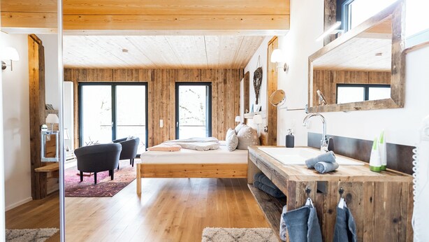A modern bedroom with a wooden ceiling, a large bed, a wooden vanity, and a large window. - Kai vacation chalet in Essing—sleeps 2 to 5 people, ideal for families! (Essing)