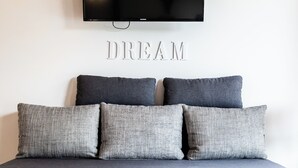 A bed with grey bedding and pillows, a mounted TV above it, and the word "DREAM" on the wall. - Kai vacation chalet in Essing—sleeps 2 to 5 people, ideal for families! (Essing)