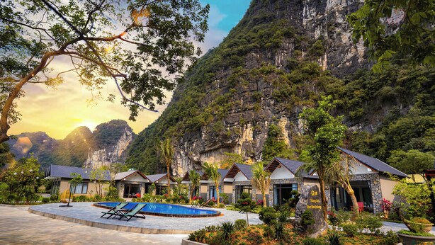A resort with a swimming pool, multiple guest rooms, and a mountainous backdrop.