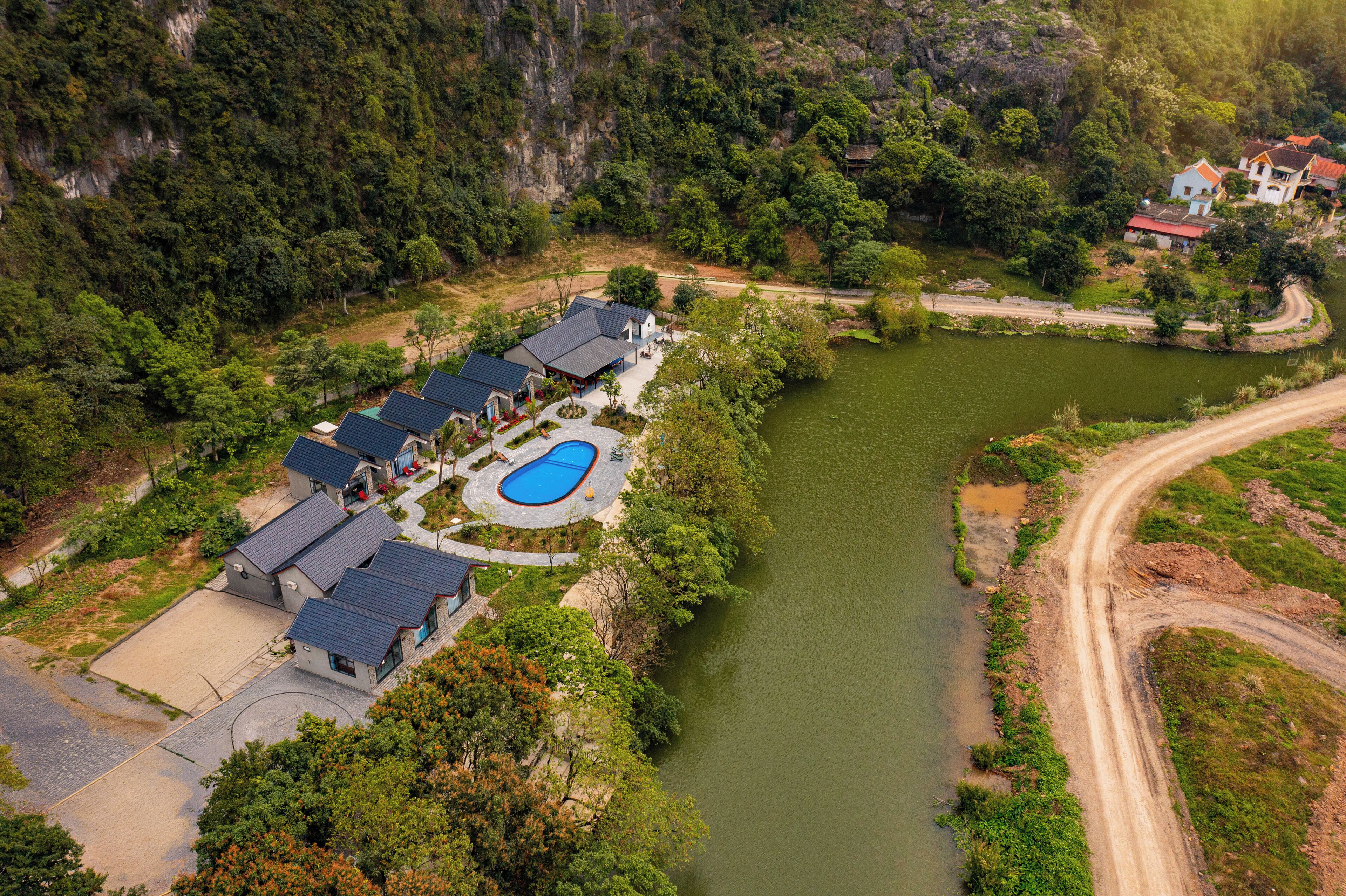 An aerial view of a resort with multiple buildings, a swimming pool, and a river.