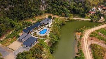 An aerial view of a resort with multiple buildings, a swimming pool, and a river.