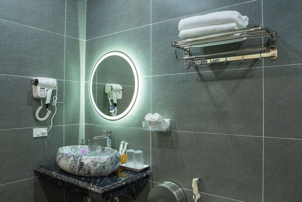 A bathroom with a marble sink, a round mirror with a light, a hairdryer, a towel rack, and a soap dispenser. - Trang An River View Ecolodge (Tay Hoa Lu)