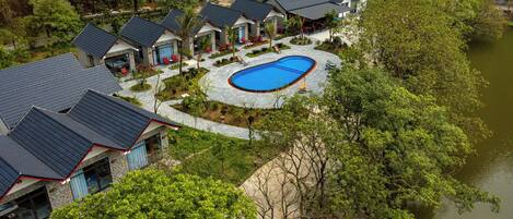 A resort with multiple buildings, a swimming pool, and a lake.
