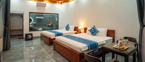 A hotel room with two beds, a wooden ceiling, a large window, a small table with a tray, and a chair.