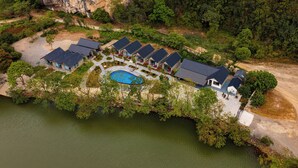An aerial view of a resort with multiple buildings, a swimming pool, and a natural surrounding.