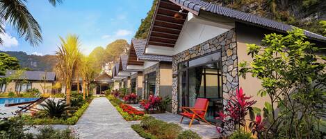 A resort with a stone pathway, outdoor seating, and a pool.