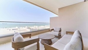 Un balcón con vista al mar, amoblado con un sofá, sillas y una mesa redonda.