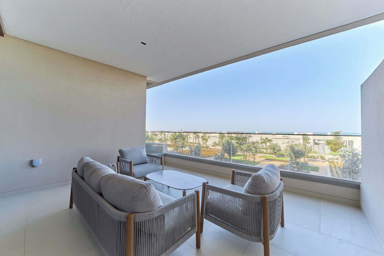 Een balkon met een bank, stoelen en een tafel.